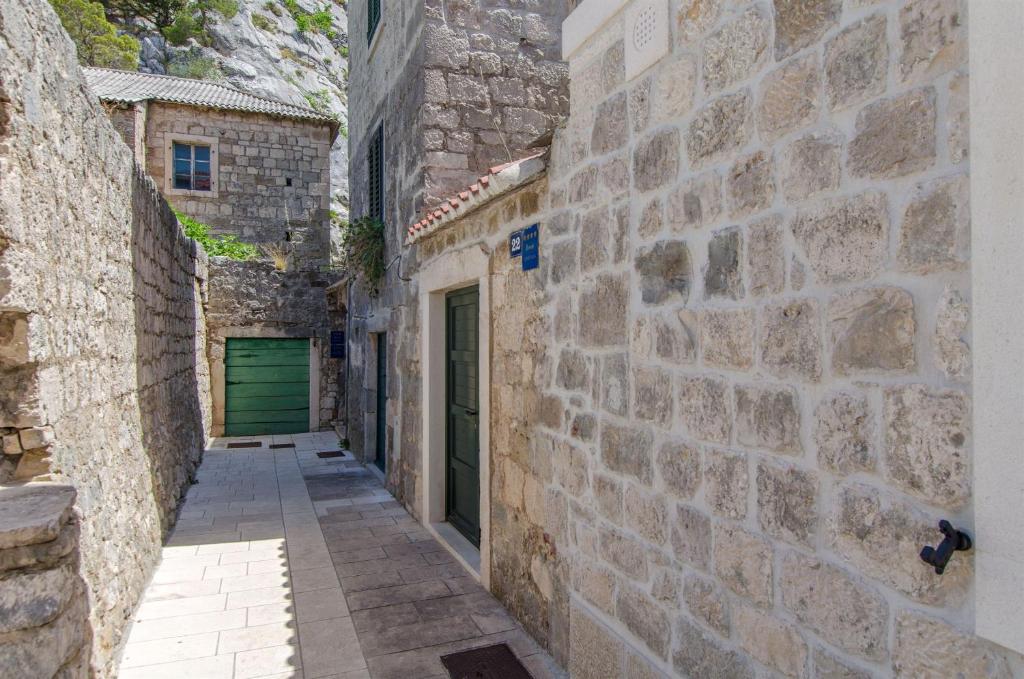 an alley with stone walls and a green door at Apartments Mira in Omiš