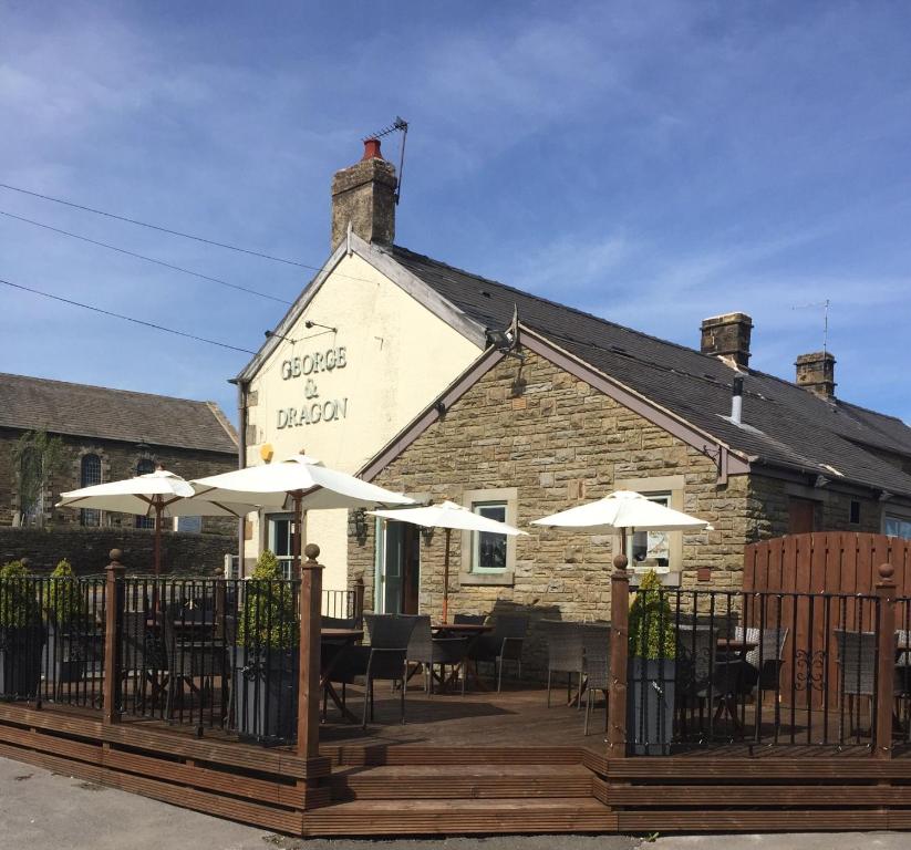 a restaurant with tables and umbrellas in front of a building at George and Dragon in Holmesfield
