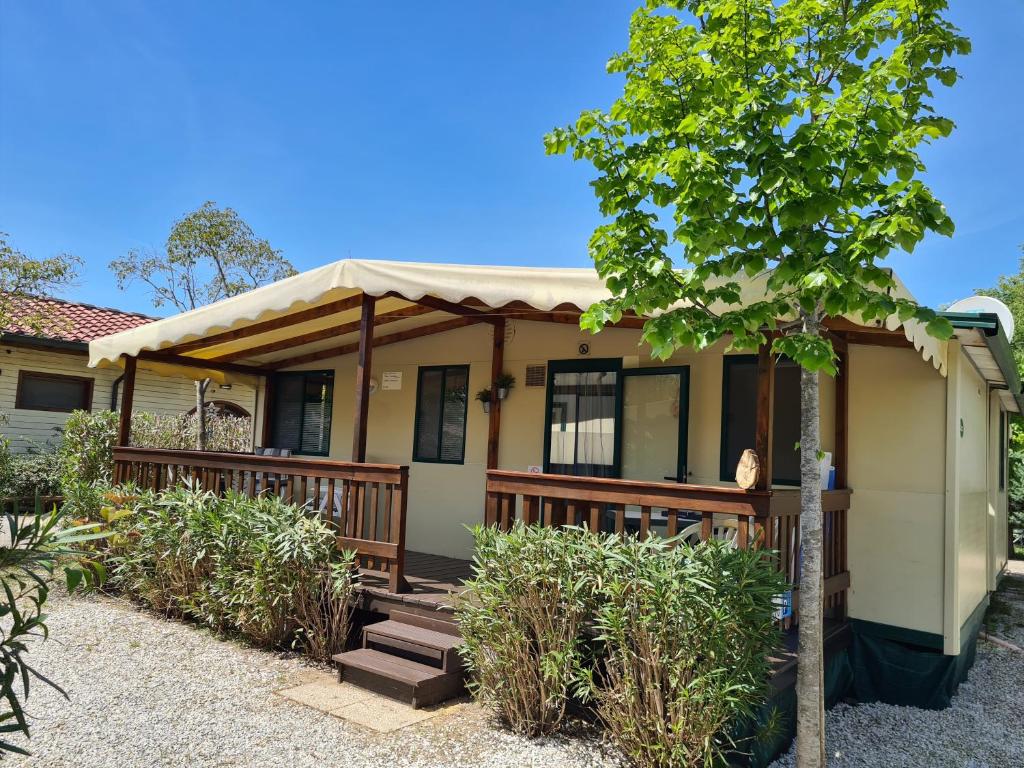 een huis met een veranda en een boom bij Chalet La Dolce Vita Viareggio in Viareggio