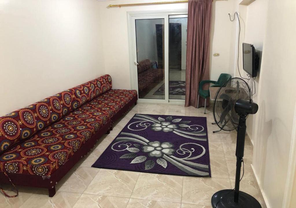 een woonkamer met een bank en een glazen deur bij AC, Wi-Fi Shahrazad Beach Apartment-2 in Alexandrië