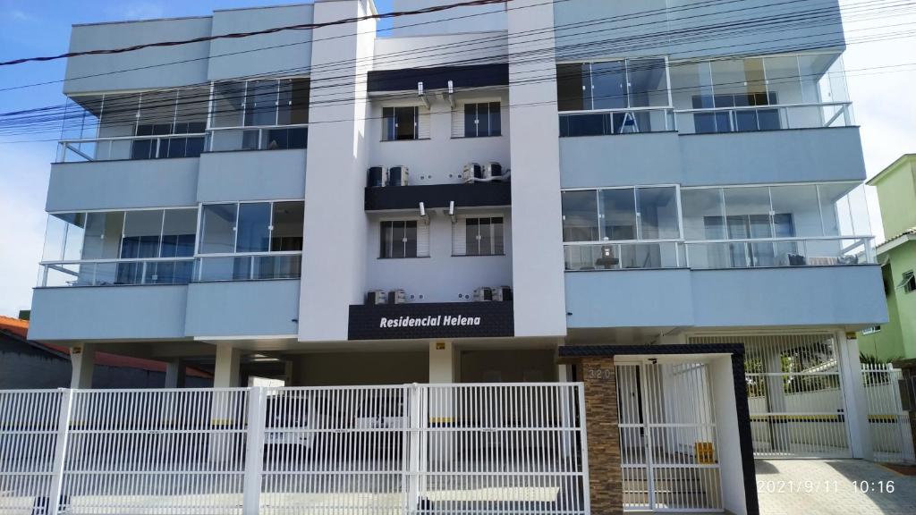 a building with a white fence in front of it at Residencial Helena in Porto Belo