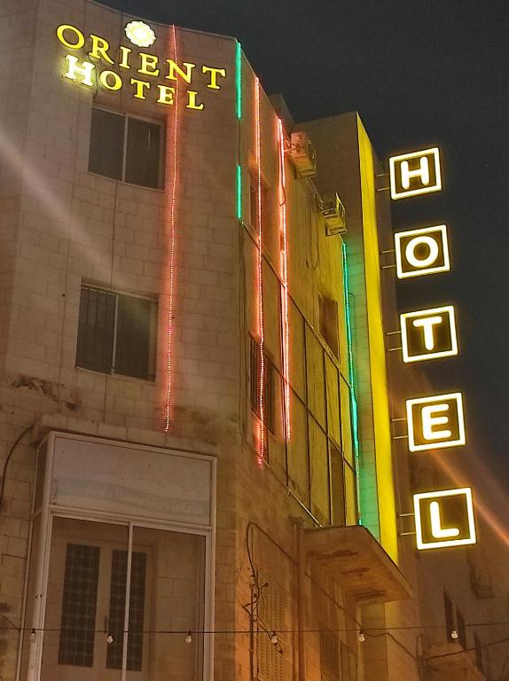 un hôtel avec des panneaux de néon sur le côté d'un bâtiment dans l'établissement Orient Hotel, à Naplouse