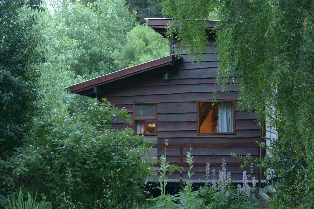 una baita di tronchi nel bosco con finestra di Hospedaje Las Gardenias a Lago Puelo