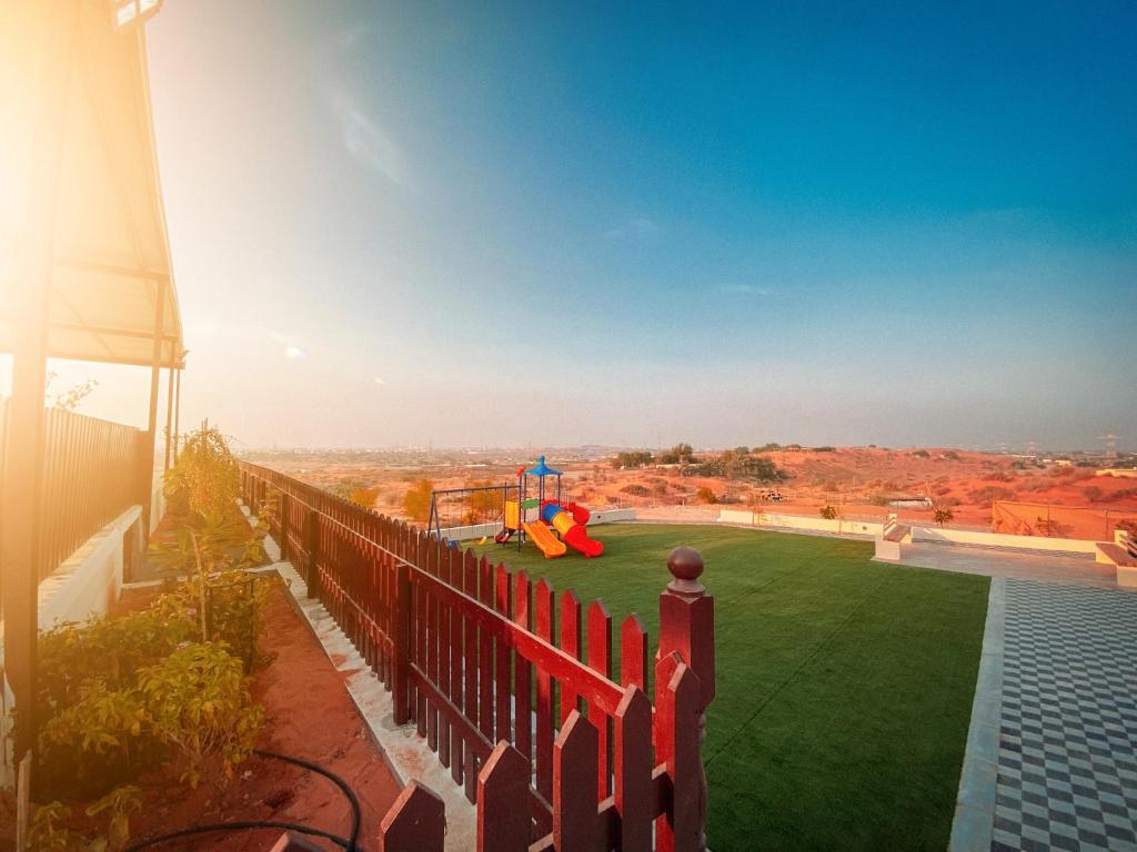 a fence on the side of a house with a green yard at Desert Dune Farmhouse - By Seven Elements in Ras al Khaimah