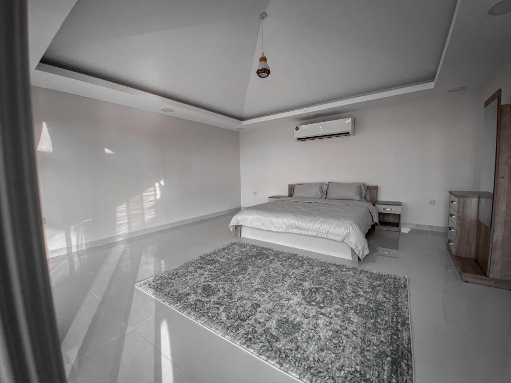a white bedroom with a bed and a rug at Desert Dune Farmhouse - By Seven Elements in Ras al Khaimah