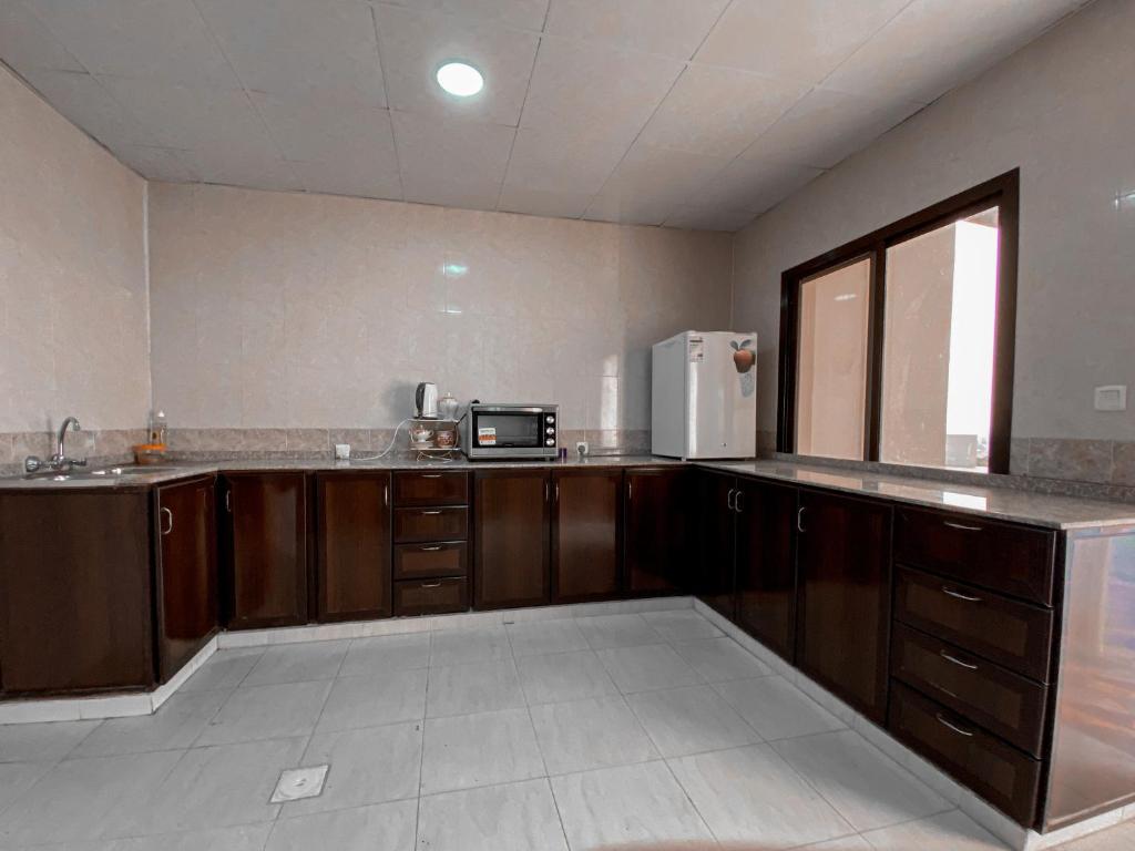 a kitchen with wooden cabinets and a microwave at Desert Dune Farmhouse - By Seven Elements in Ras al Khaimah