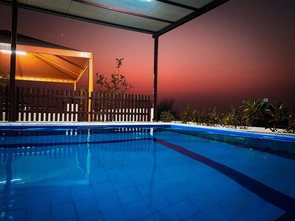 a large swimming pool at night with aophe at Desert Dune Farmhouse - By Seven Elements in Ras al Khaimah