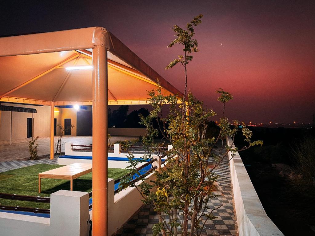 a rooftop garden with a swimming pool at night at Desert Dune Farmhouse - By Seven Elements in Ras al Khaimah