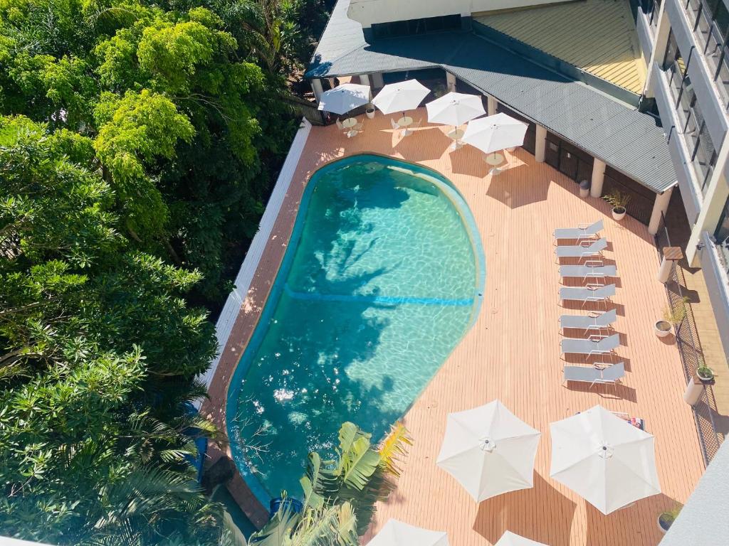 uma vista sobre uma piscina com guarda-sóis e cadeiras em Greenmount Beach House em Gold Coast
