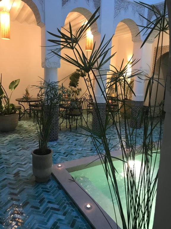 un patio con piscina, mesas y plantas en Riad Dollar Des Sables & Spa, en Marrakech