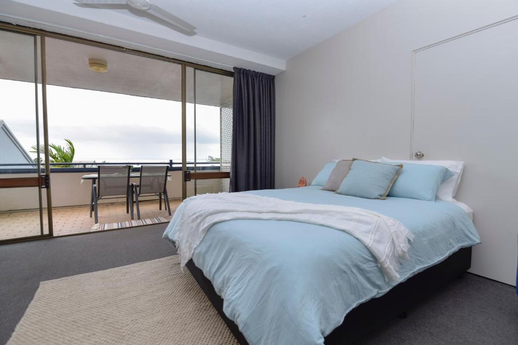 a bedroom with a bed with a view of a balcony at Studio Apartment, Centre Of Airlie With Sea Views in Airlie Beach