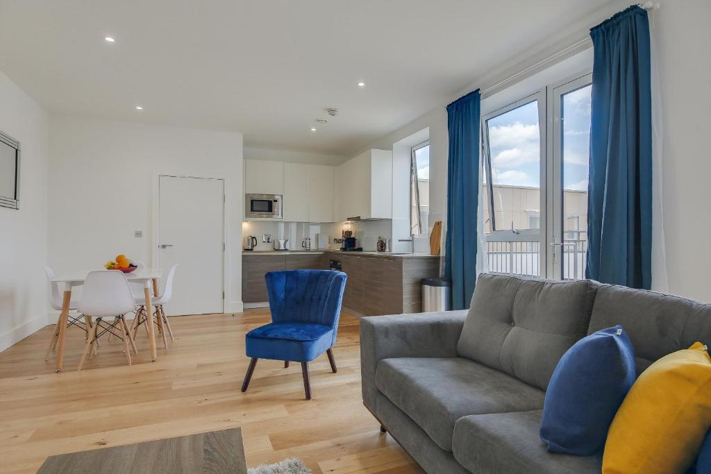 a living room with a gray couch and blue chairs at Modern & Spacious Studio & One Bedroom Apartments in Heathrow in Hounslow