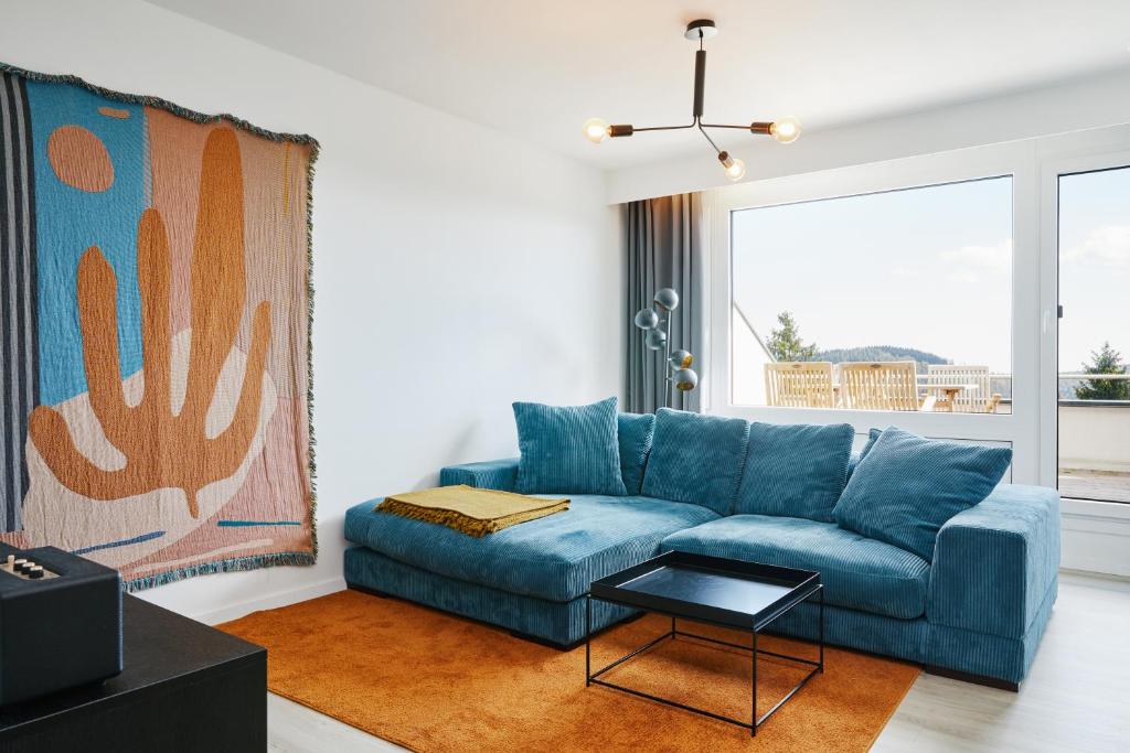 een woonkamer met een blauwe bank en een tafel bij Welcome in - Appartement 'Buena Vista' met een dakterras en berging, dichtbij de pistes in Winterberg