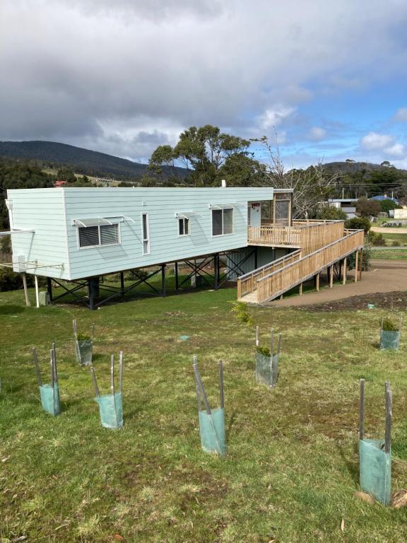 a white house with a deck and a staircase at Bruny Ocean Cottage in Alonnah