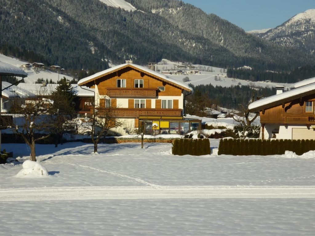 ein großes Holzhaus im Schnee mit Bergen in der Unterkunft Haus Gabriela in Itter