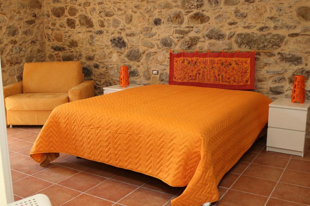 1 dormitorio con 1 cama de color naranja y 1 silla en Il Vicolo, en Tortorici