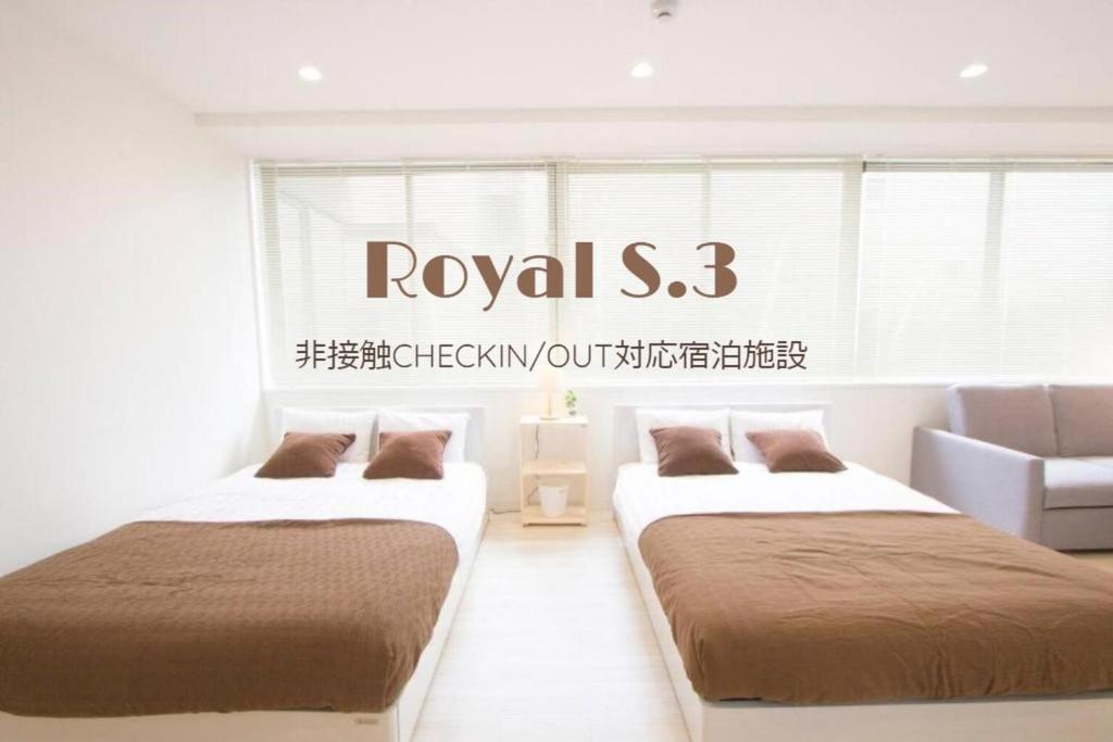 札幌市にあるCozy and Convenient Royal heightsのベッド2台 壁に看板が付いた部屋