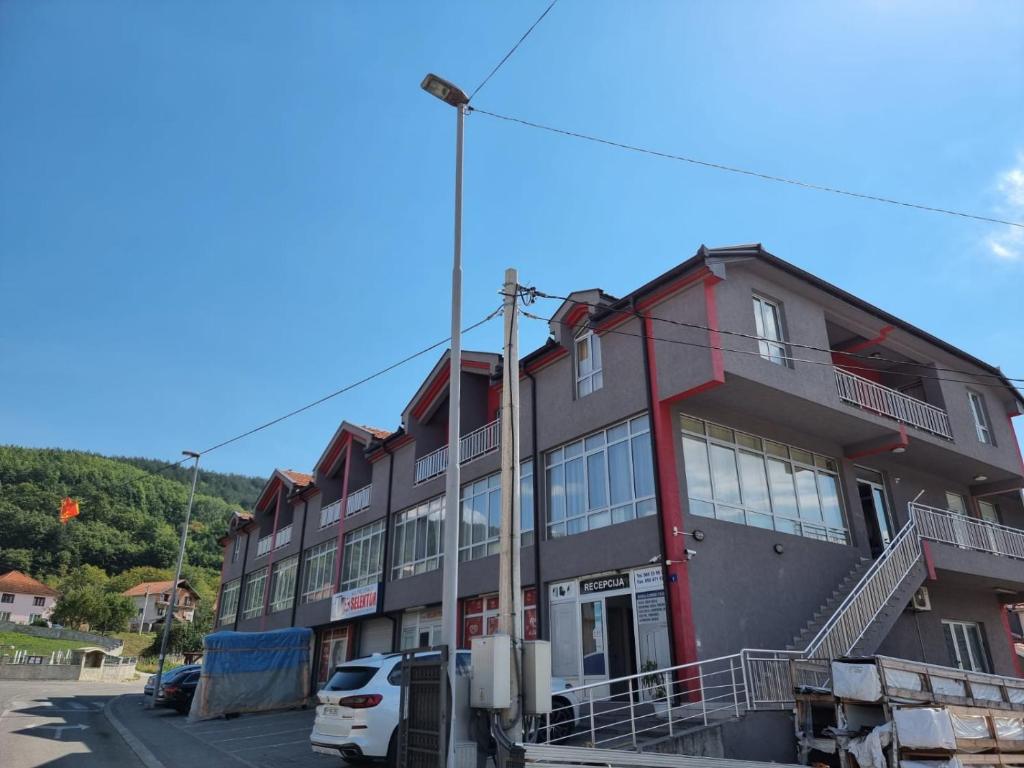 a red building with cars parked in front of it at Apartmani Selektor in Bijelo Polje