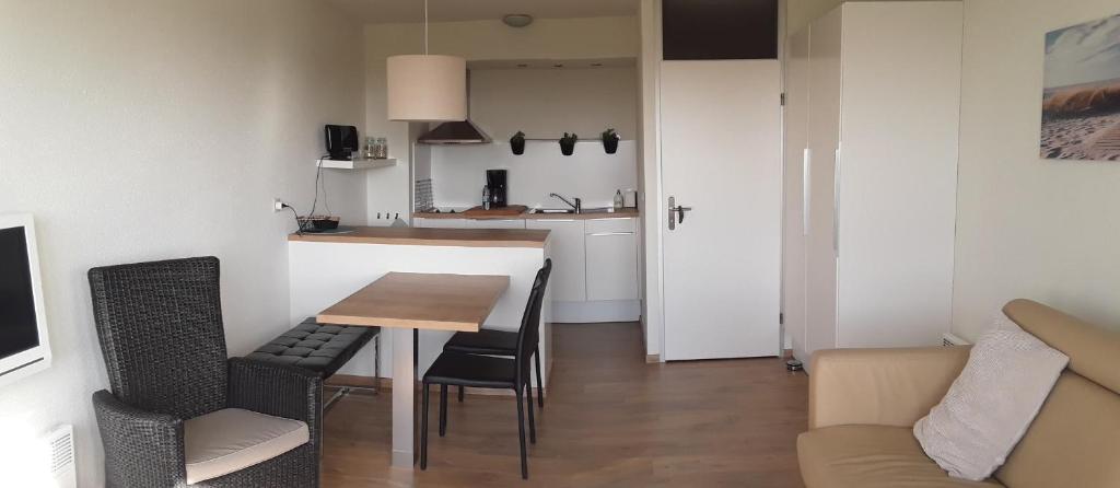um pequeno apartamento com uma mesa e cadeiras e uma cozinha em Vakantiestudio De Zeeparel De Panne met Zwembad em De Panne