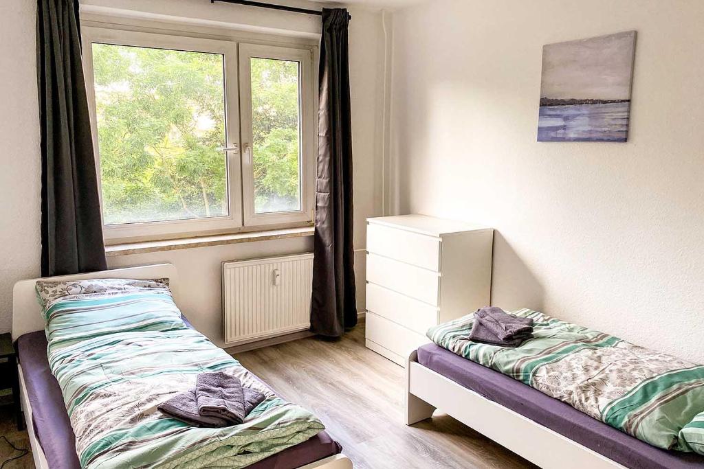 a bedroom with two beds and a window at City-Apartment Halle mit TV und WLAN in Angersdorf