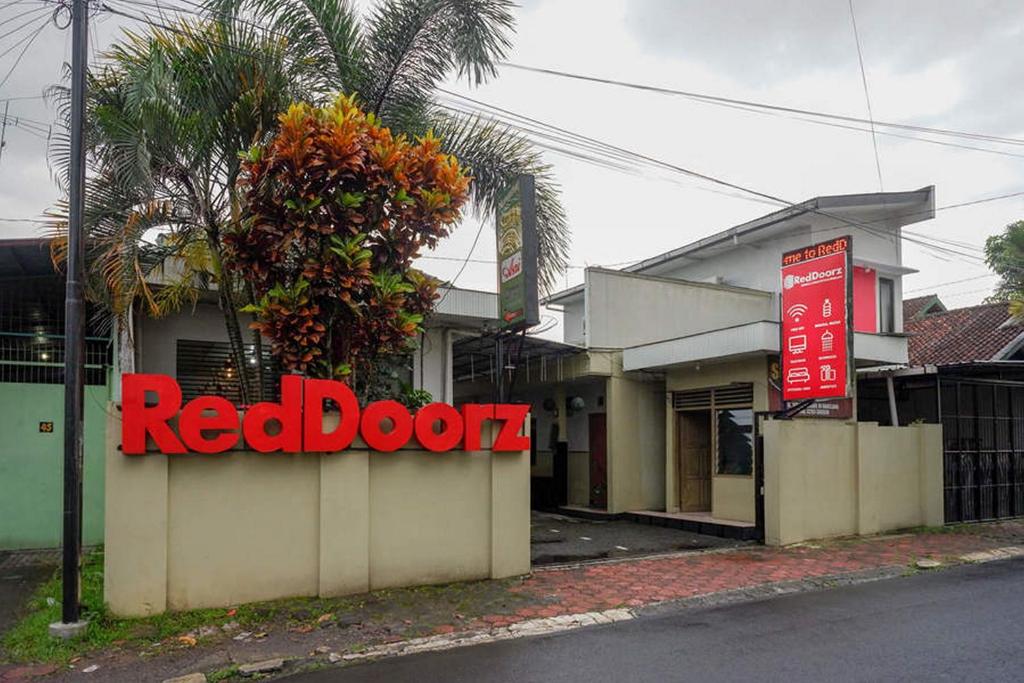 un panneau de porte rouge devant un bâtiment dans l'établissement RedDoorz Syariah @ Sunan Bonang Magelang, à Magelang