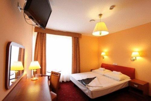 a hotel room with a bed and a television at OKRĄGLAK Residence Sosnowiec in Sosnowiec