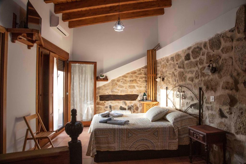 - une chambre avec un lit et un mur en pierre dans l'établissement El Capricho 2, à Villamiel