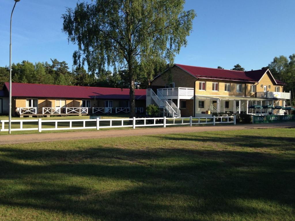 a house with a white fence in front of a field at Böda Hotell in Böda