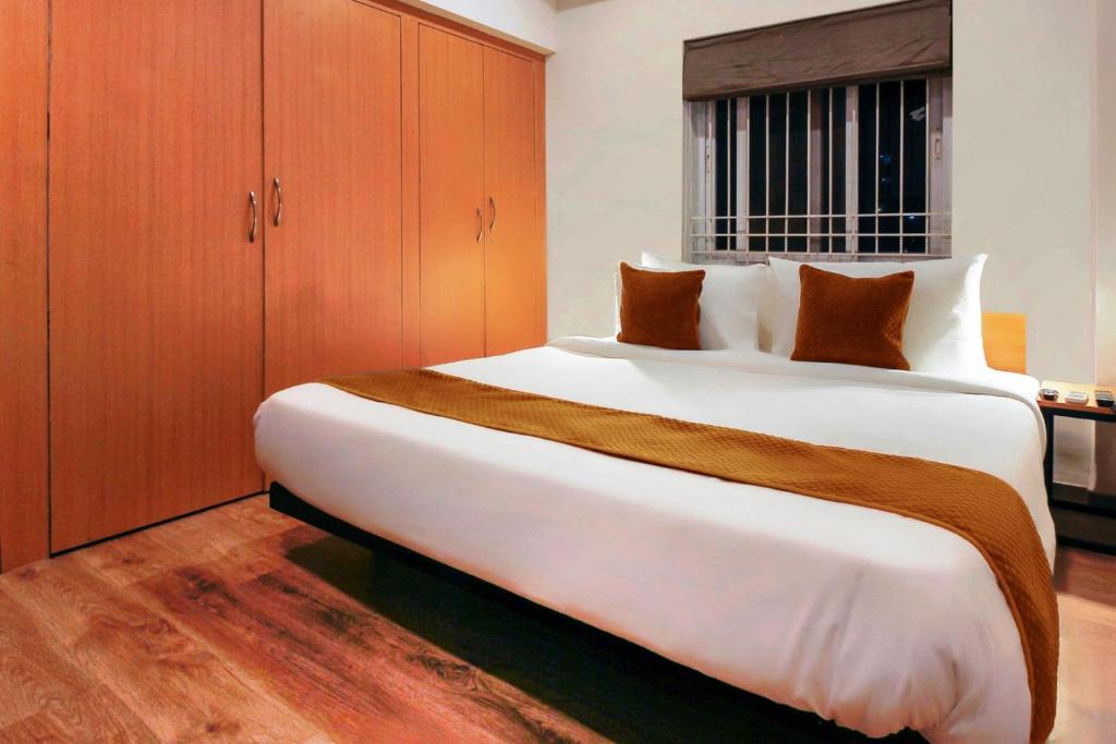 a bedroom with a large white bed with wooden cabinets at Hotel Mallikarjuna Residency in Hyderabad