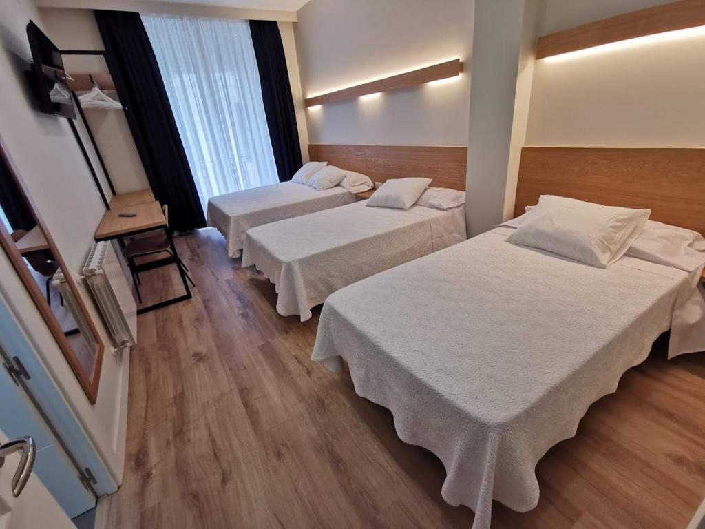 Una habitación de hotel con dos camas y una ventana. en Plaza Pombo B&B - Hostal, en Santander