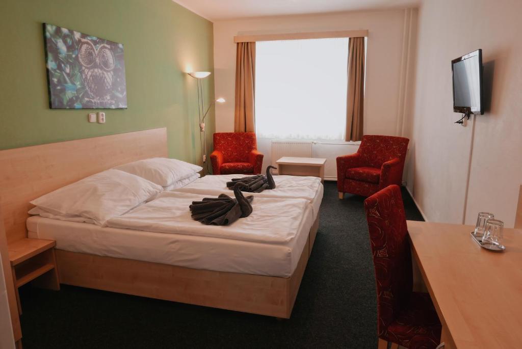 a hotel room with a bed and two red chairs at Městský hotel Bobík in Volary