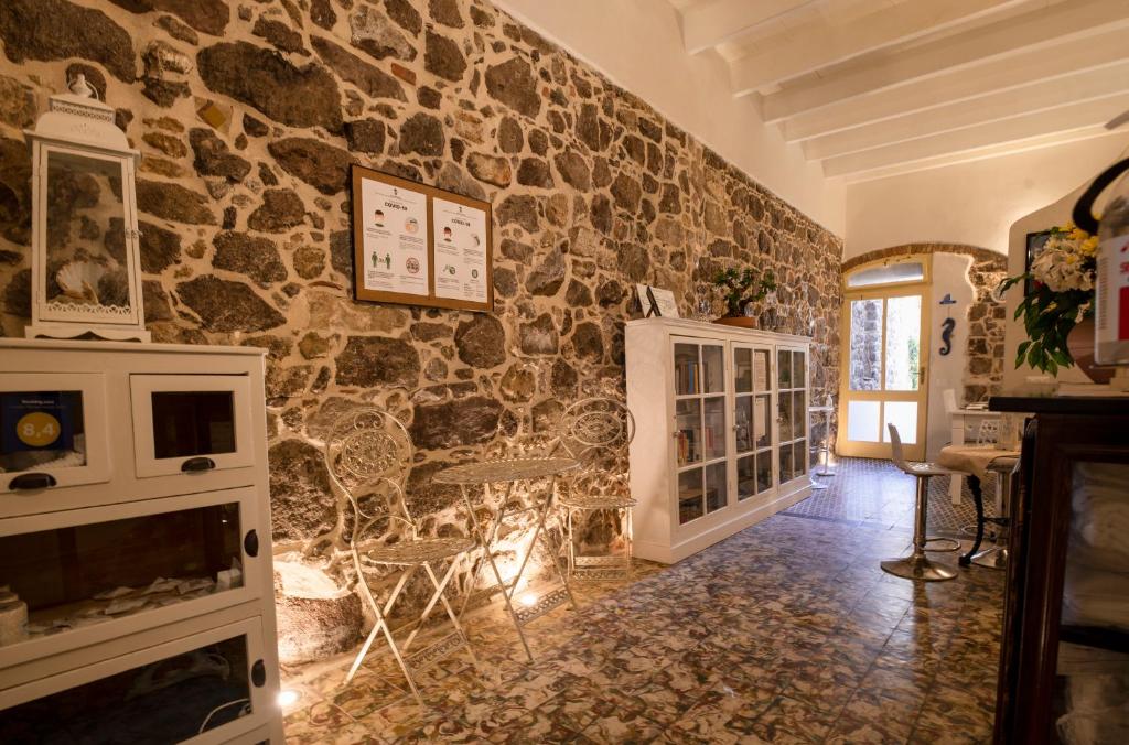 a room with a stone wall with a table and chairs at Domo Sa Barra in SantʼAntìoco
