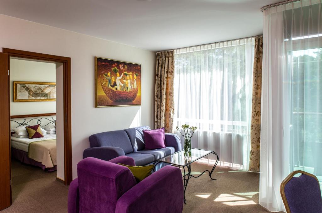 ein Wohnzimmer mit lila Stühlen und einem Bett in der Unterkunft MEDEA Apartments by UPA in Druskininkai