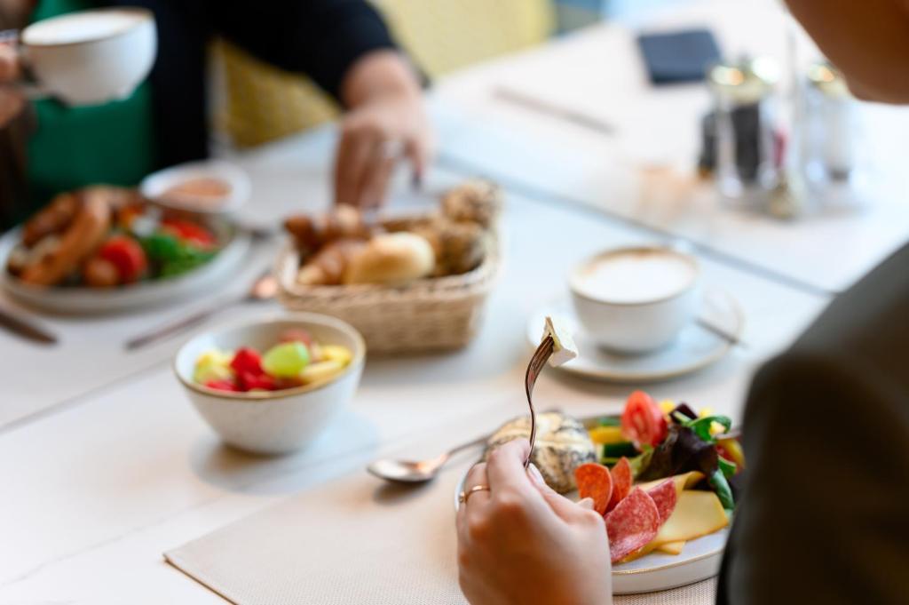 a person sitting at a table with a plate of food at Hotel Vision Budapest by Continental Group in Budapest