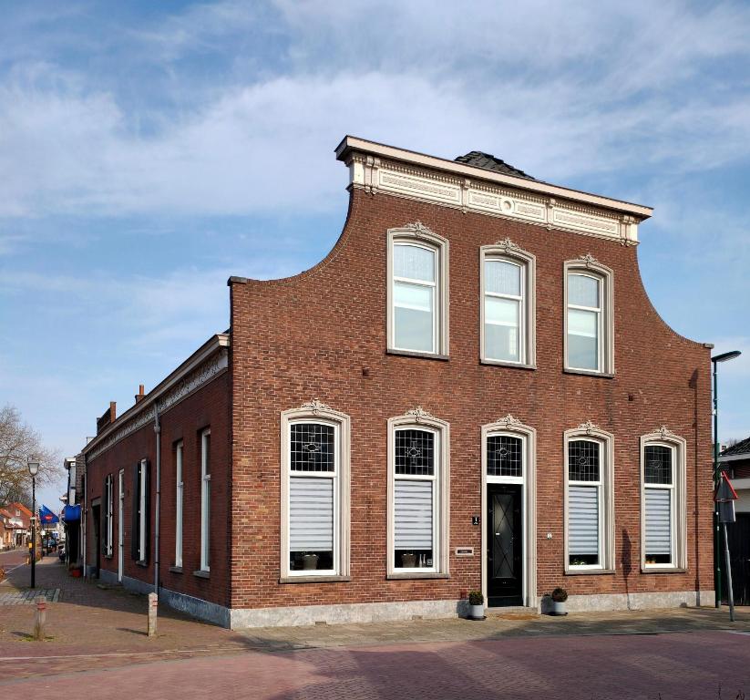 un edificio di mattoni rossi con tetto di gamberetti di B&B Het Voorhuis a Loon op Zand