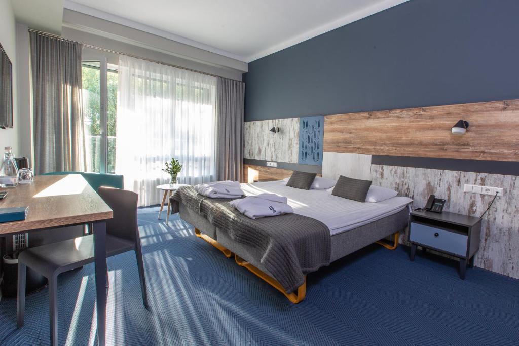 een slaapkamer met een groot bed en een bureau bij UPA Medical SPA in Druskininkai