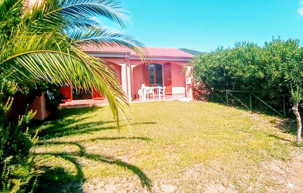 uma casa cor-de-rosa com uma palmeira no quintal em Il mirto e l'oleandro em Teulada