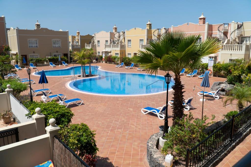einen Pool mit Stühlen und Palmen in einem Resort in der Unterkunft Sunset Rooftop Terrace apartment in Palm-mar