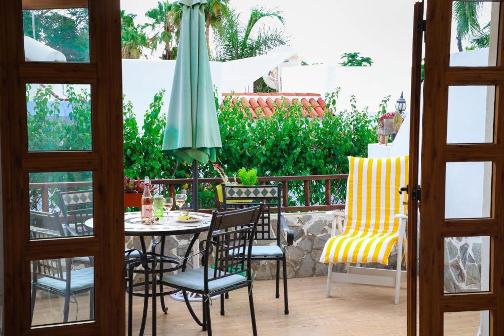 une terrasse avec une table, des chaises et un parasol dans l'établissement Los Geranios, Close to BEACH, Puerto Colon, YellowCat 2, à Adeje