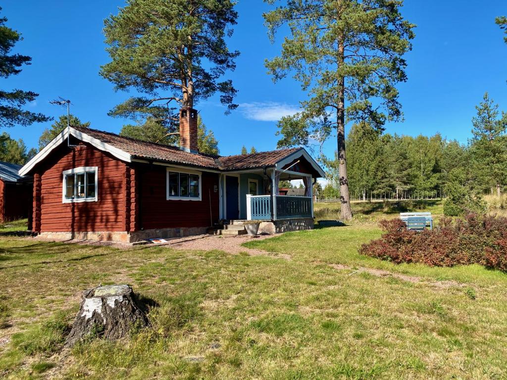una pequeña casa roja con un porche en un patio en Hansjö stugby - Topersvägen, en Orsa