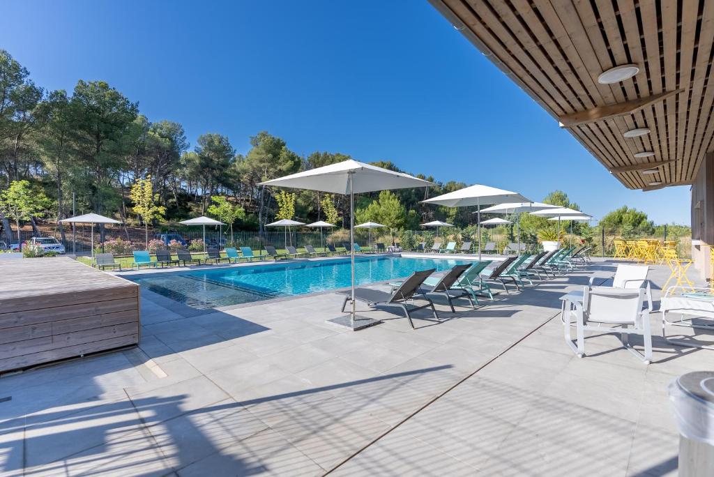 - une piscine avec des chaises longues et des parasols dans l'établissement Kyriad Résidence Cabriès - Plan de Campagne, à Cabriès