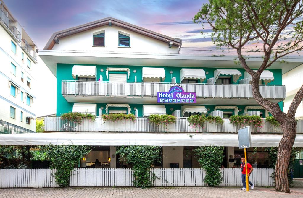 a person walking in front of a hotel complex at Hotel Olanda in Lido di Jesolo