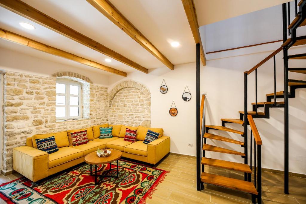 a living room with a yellow couch and a staircase at Vila Leon - Old Qeparo in Qeparo