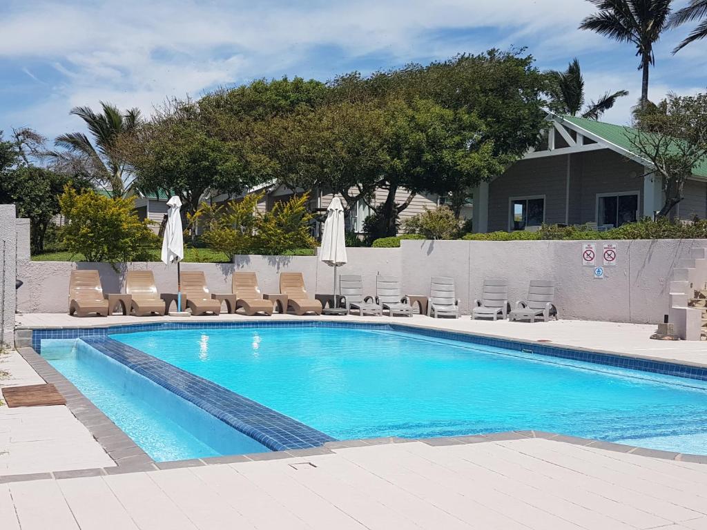 a swimming pool with chairs and umbrellas at Praia do Cossa in Vila Praia Do Bilene