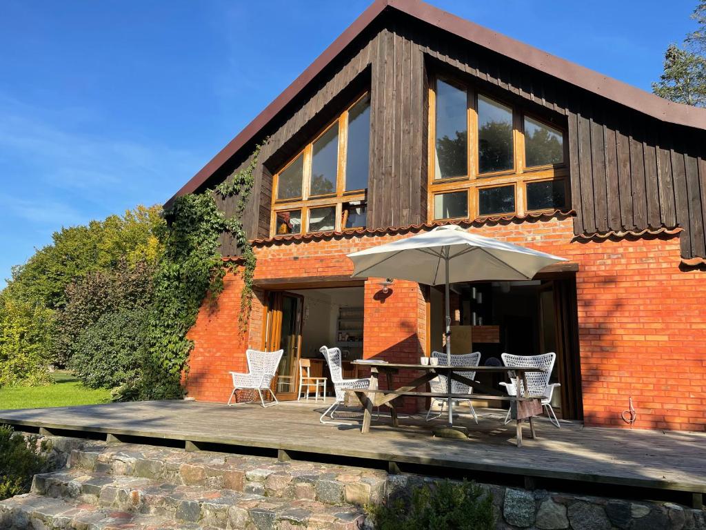 a brick house with a table and chairs and an umbrella at Mamrowisko in Węgorzewo