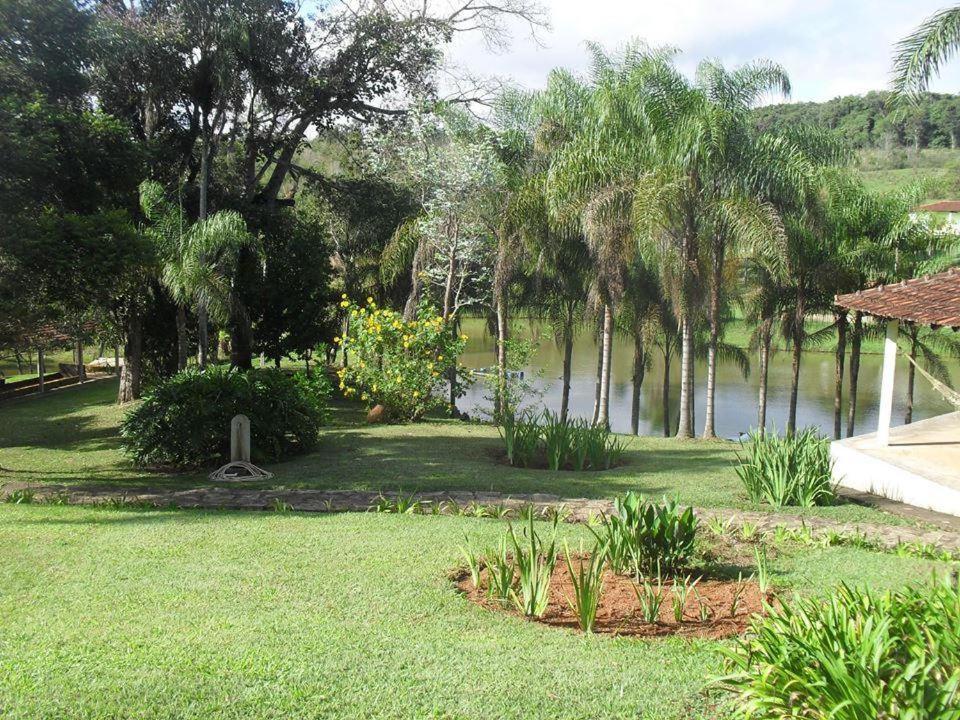 a garden with trees and a body of water at Pousada Encanto da Mata - Ecológica in Caconde