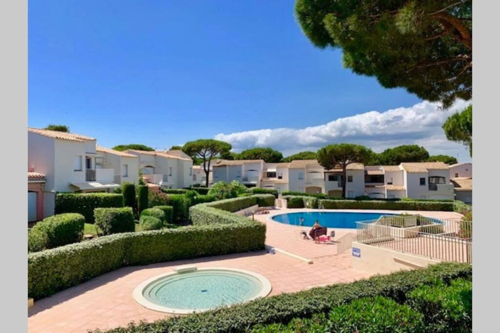 un complexe avec une piscine et quelques buissons dans l'établissement Cap d'Agde appart. 4/6 pers. avec jardin, piscine., au Cap d'Agde