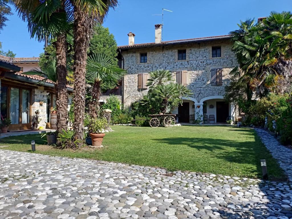 una casa con palme e un vialetto in pietra di B & B Rovere dalla riva a Arzene