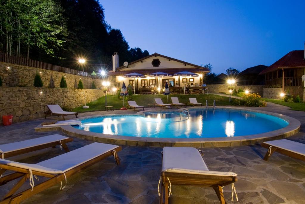 a swimming pool with lounge chairs around it at night at Complex Balgarka in Tryavna