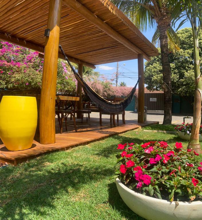 a patio with a hammock and a table and flowers at Castelo Inn Hotel in Goiânia